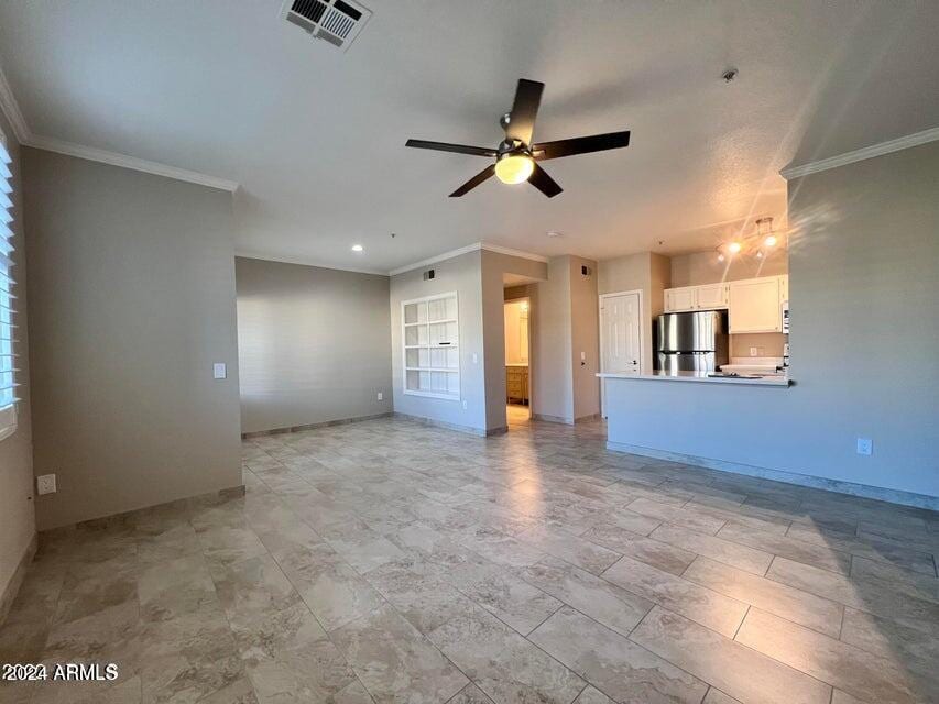 unfurnished living room featuring built in shelves, ceiling fan, and ornamental molding