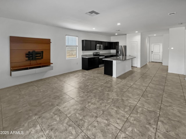 kitchen with a kitchen island with sink, light tile patterned floors, and stainless steel appliances