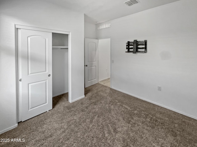 unfurnished bedroom featuring light carpet and a closet