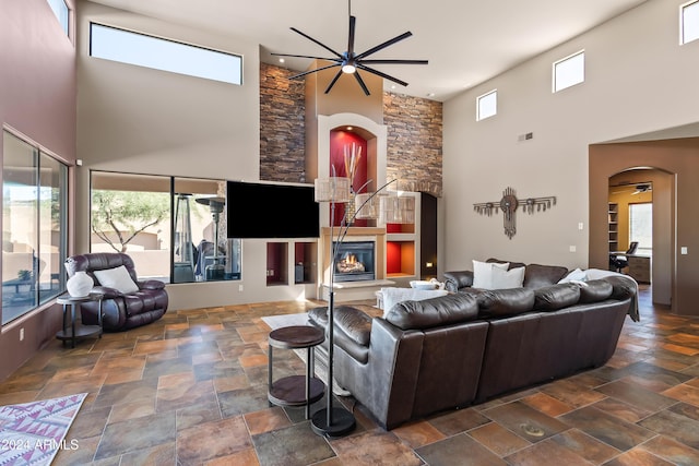15406 E Cavedale Dr, Scottsdale, AZ 85262 - living room with a towering ceiling, arched walkways, a ceiling fan, stone tile flooring, and a glass covered fireplace