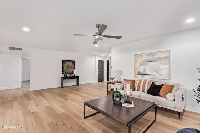 living room with a ceiling fan, visible vents, light wood-style flooring, and baseboards