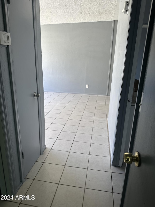 corridor with light tile patterned floors and a textured ceiling