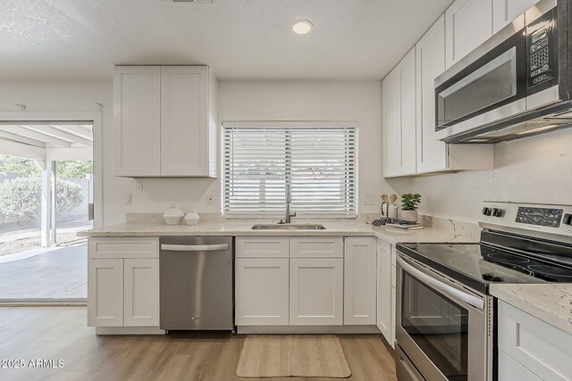 16421 N 34th Ave, Phoenix, AZ 85053 - kitchen featuring stainless steel appliances, light wood-style floors, white cabinets, light stone counters, and recessed lighting