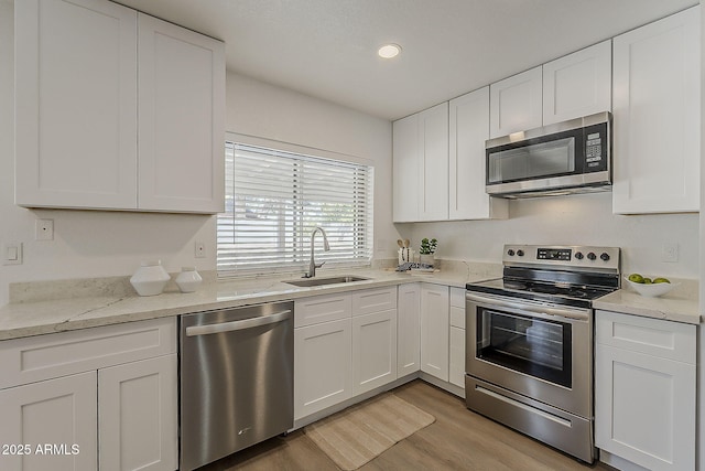16421 N 34th Ave, Phoenix, AZ 85053 - kitchen featuring stainless steel appliances, white cabinets, light wood-style floors, light stone countertops, and recessed lighting