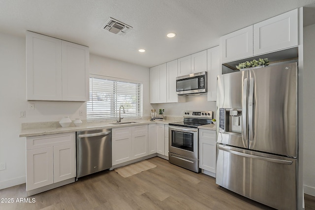 16421 N 34th Ave, Phoenix, AZ 85053 - kitchen featuring appliances with stainless steel finishes, white cabinets, light wood-type flooring, recessed lighting, and light stone countertops