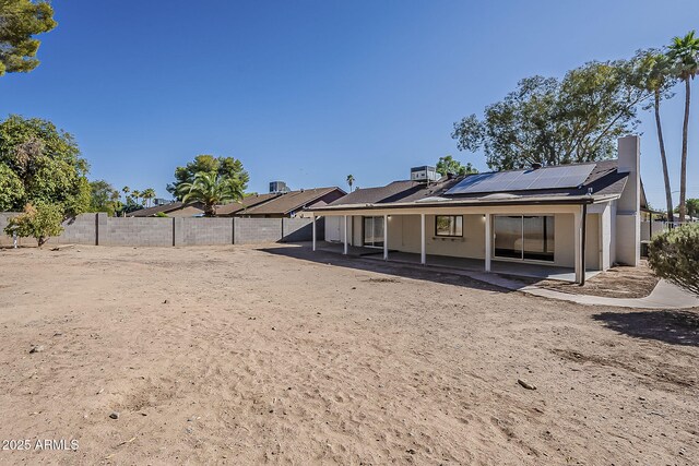 16421 N 34th Ave, Phoenix, AZ 85053 - back of property featuring a patio, roof mounted solar panels, a fenced backyard, and a chimney