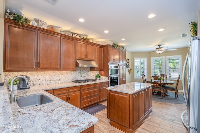 kitchen with a center island, backsplash, ceiling fan, appliances with stainless steel finishes, and sink