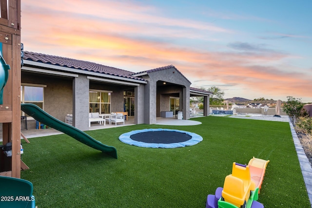 9527 W Whitehorn Way, Peoria, AZ 85383 - back of property at dusk with a tile roof, stucco siding, a patio area, and a lawn