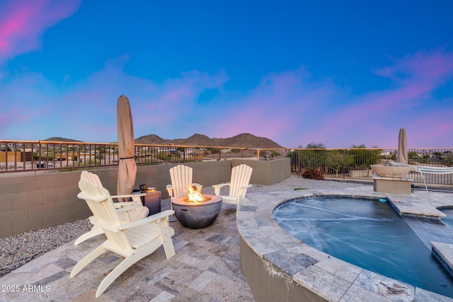 9527 W Whitehorn Way, Peoria, AZ 85383 - patio terrace at dusk with a fire pit, a patio area, a mountain view, and a pool