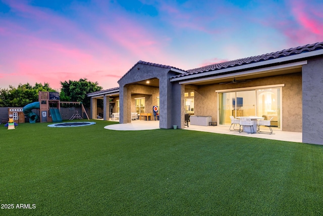 9527 W Whitehorn Way, Peoria, AZ 85383 - back of house at dusk with a playground, a patio area, a yard, and stucco siding