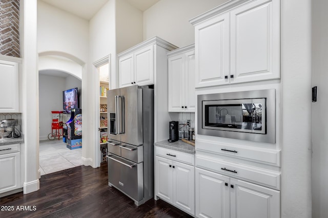 9527 W Whitehorn Way, Peoria, AZ 85383 - kitchen with appliances with stainless steel finishes, white cabinets, dark wood-style flooring, arched walkways, and baseboards