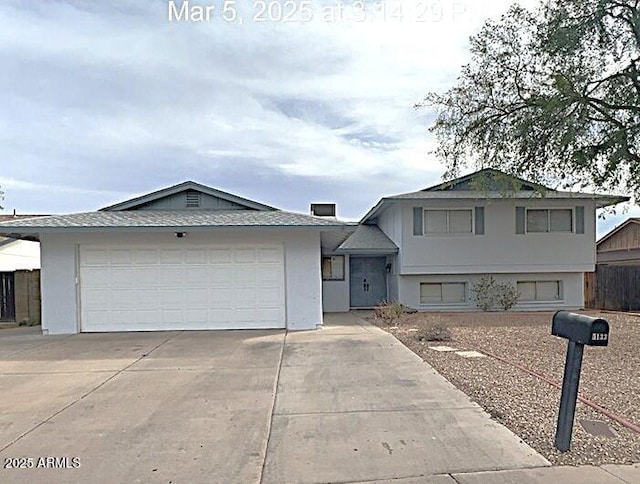 split level home with stucco siding, concrete driveway, and an attached garage