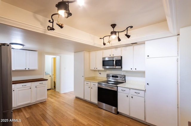 kitchen featuring stainless steel appliances, white cabinetry, washer / clothes dryer, and light wood finished floors