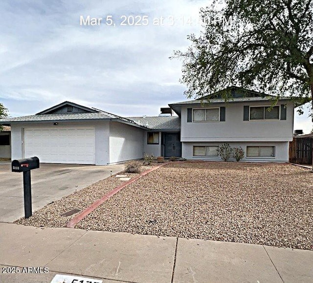 tri-level home featuring stucco siding, an attached garage, and concrete driveway