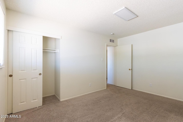 unfurnished bedroom with visible vents, baseboards, carpet floors, a closet, and a textured ceiling