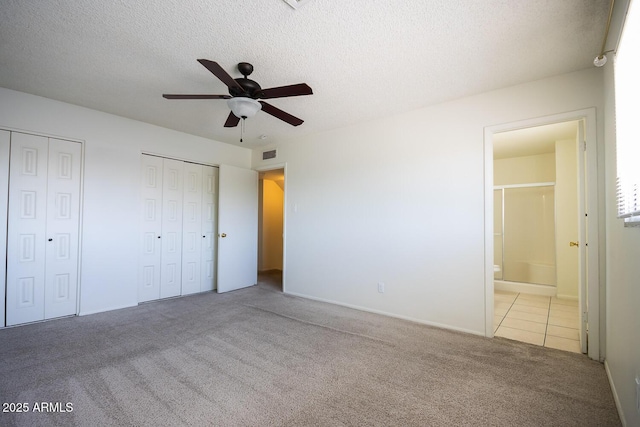 unfurnished bedroom featuring visible vents, two closets, a textured ceiling, connected bathroom, and carpet