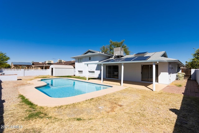 back of property with a patio, roof mounted solar panels, central AC, a fenced backyard, and a fenced in pool