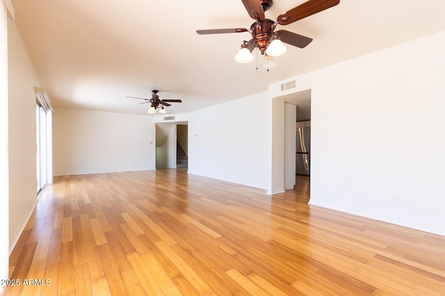 spare room with visible vents, stairway, light wood-type flooring, and ceiling fan