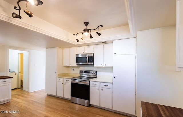 kitchen featuring a tray ceiling, washer / clothes dryer, stainless steel appliances, white cabinets, and light wood-type flooring