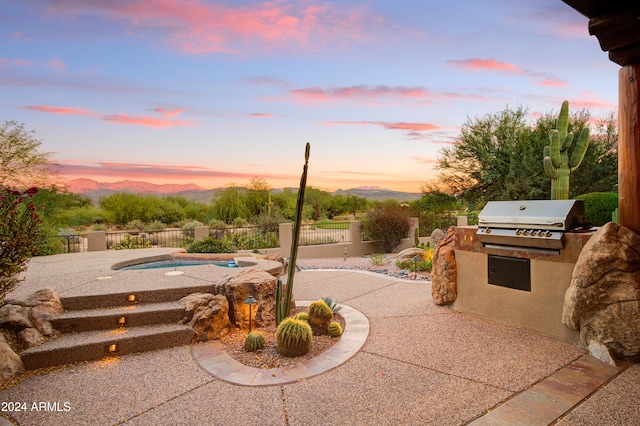 patio terrace at dusk featuring a mountain view, area for grilling, and a fenced in pool