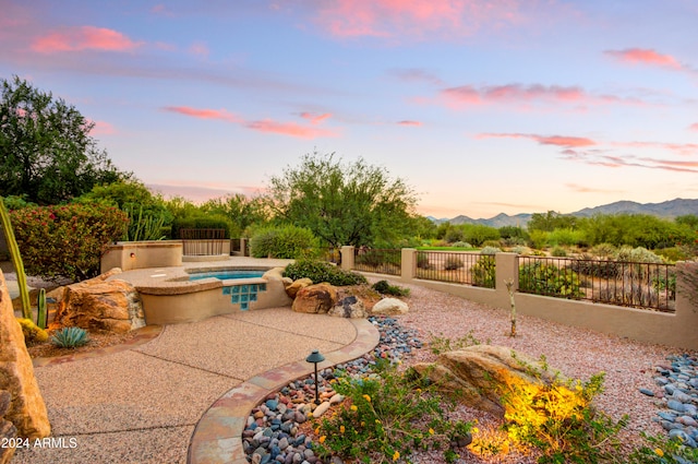 patio terrace at dusk with a mountain view and a pool with hot tub