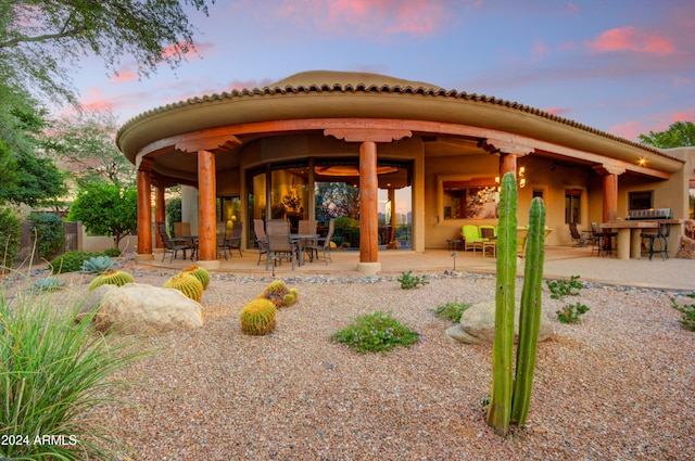 back house at dusk featuring a patio