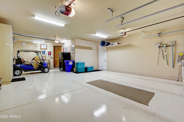 garage with a garage door opener and black refrigerator