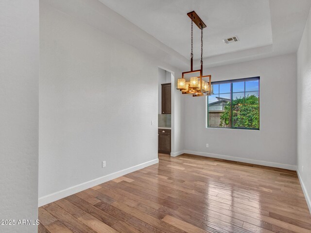 3809 E Lynx Pl, Chandler, AZ 85249 - empty room featuring light wood finished floors, a chandelier, baseboards, and a raised ceiling
