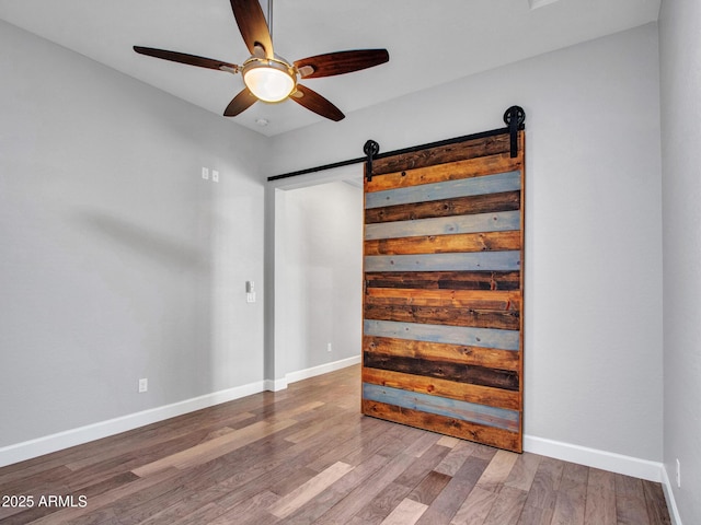 3809 E Lynx Pl, Chandler, AZ 85249 - unfurnished bedroom featuring a barn door, wood finished floors, baseboards, and a ceiling fan
