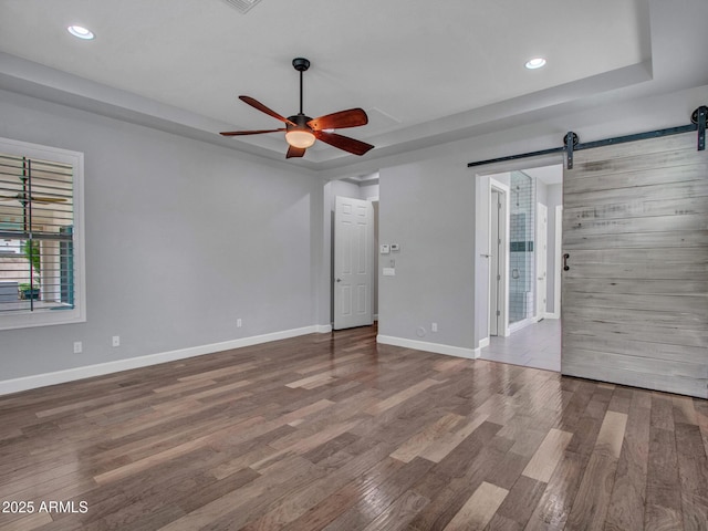 3809 E Lynx Pl, Chandler, AZ 85249 - unfurnished room with a barn door, a tray ceiling, ceiling fan, wood finished floors, and recessed lighting