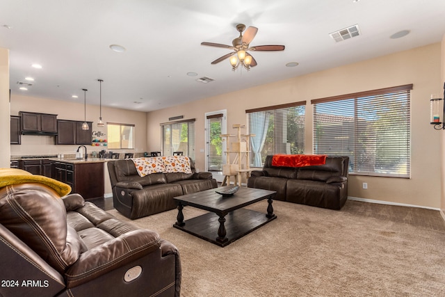 living room featuring ceiling fan, sink, and light colored carpet