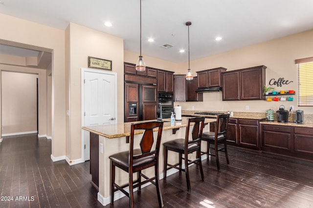 kitchen featuring a center island with sink, paneled fridge, hanging light fixtures, and dark hardwood / wood-style floors