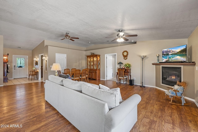 living room with a textured ceiling, ceiling fan, hardwood / wood-style floors, and vaulted ceiling