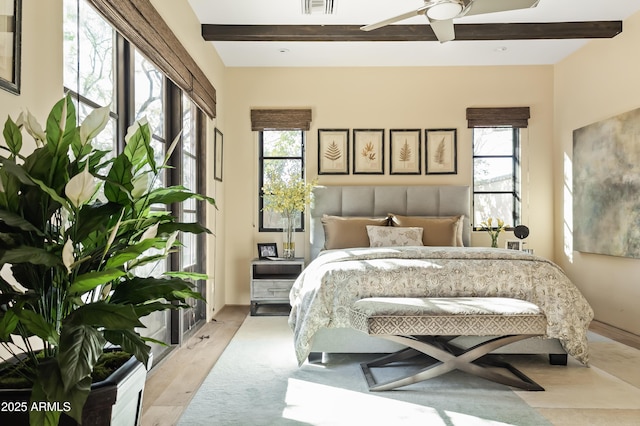 bedroom with beamed ceiling, light wood-type flooring, and ceiling fan