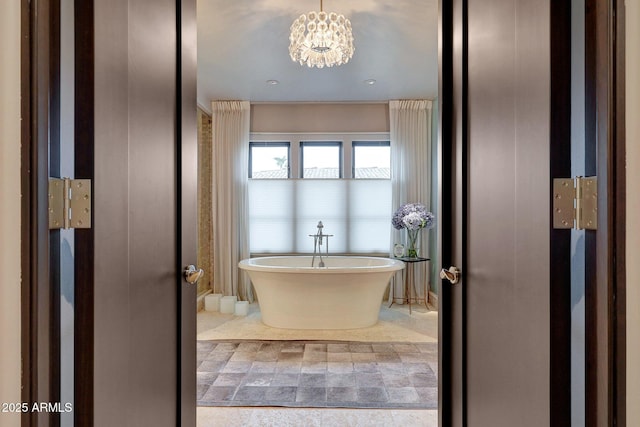 bathroom featuring an inviting chandelier and a bathtub