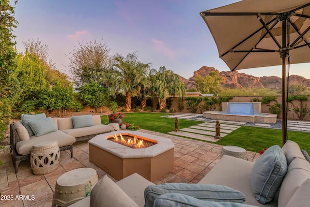 patio terrace at dusk with a mountain view and an outdoor living space with a fire pit