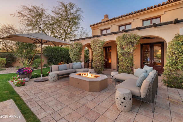 patio terrace at dusk with french doors and an outdoor living space with a fire pit