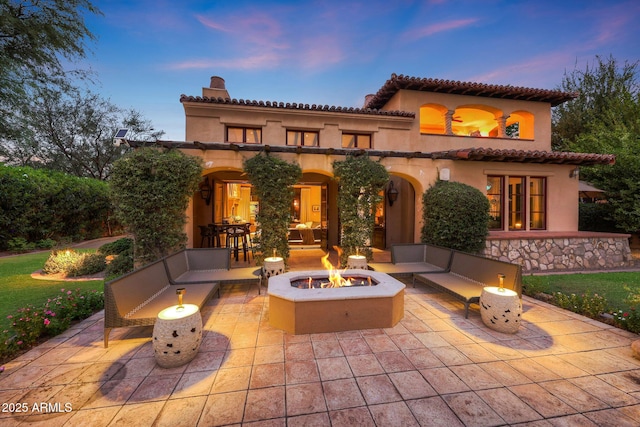 back house at dusk with a patio area and an outdoor living space with a fire pit