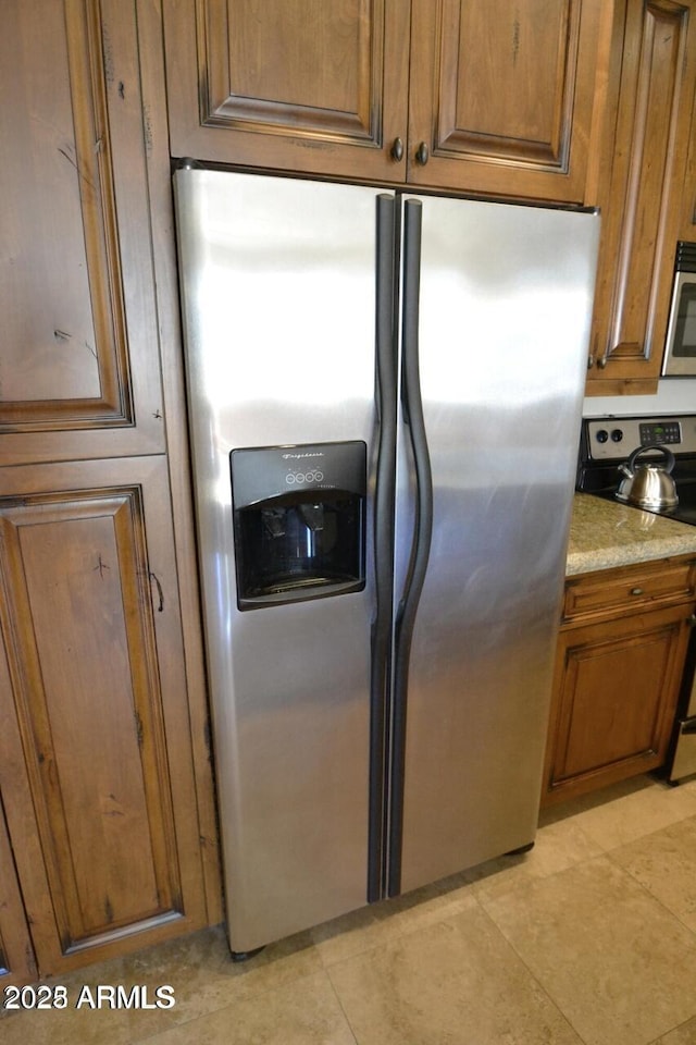 5345 E Van Buren St Unit 115, Phoenix, AZ 85008 - kitchen featuring appliances with stainless steel finishes, brown cabinets, light stone counters, and light tile patterned flooring