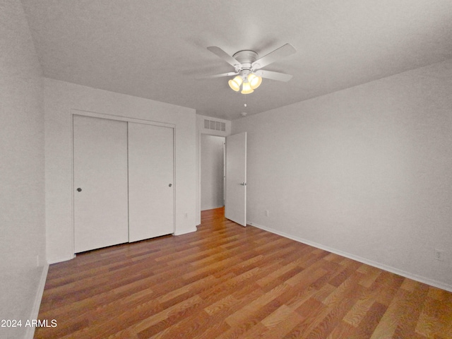 unfurnished bedroom featuring hardwood / wood-style floors, ceiling fan, and a closet