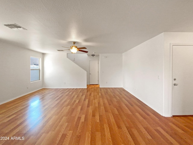 unfurnished living room featuring ceiling fan, light hardwood / wood-style floors, and a textured ceiling