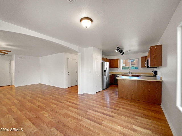 kitchen with kitchen peninsula, stainless steel fridge, light hardwood / wood-style flooring, and ceiling fan