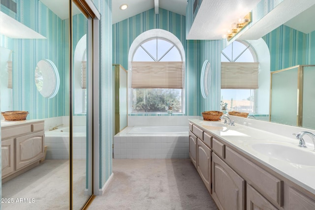 bathroom with vanity, tiled tub, and a wealth of natural light