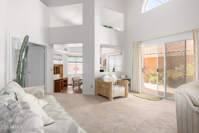 living room featuring a high ceiling, a wealth of natural light, and light colored carpet