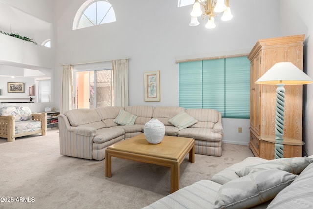 carpeted living room featuring a high ceiling, a notable chandelier, and a wealth of natural light