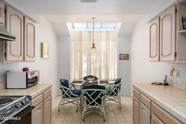 kitchen with light brown cabinetry, electric range, and tile counters