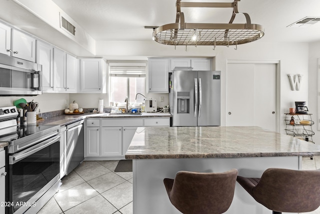 3211 E Kerry Ln, Phoenix, AZ 85050 - kitchen with visible vents, a breakfast bar, light stone countertops, appliances with stainless steel finishes, and a sink
