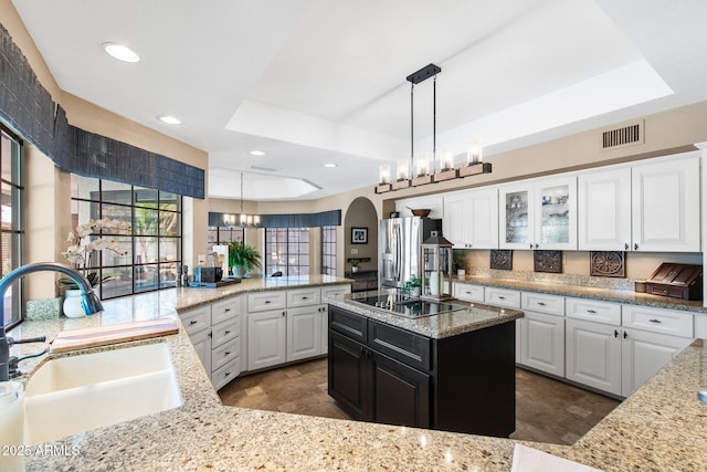 kitchen with a sink, black electric stovetop, a chandelier, stainless steel fridge with ice dispenser, and arched walkways