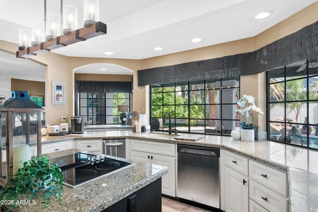 kitchen with stainless steel dishwasher, a sink, white cabinetry, light stone countertops, and recessed lighting