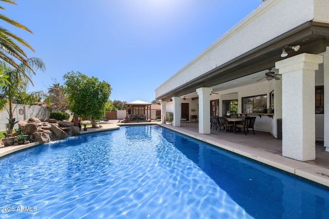 view of pool featuring ceiling fan, a patio area, fence, a gazebo, and outdoor dining area